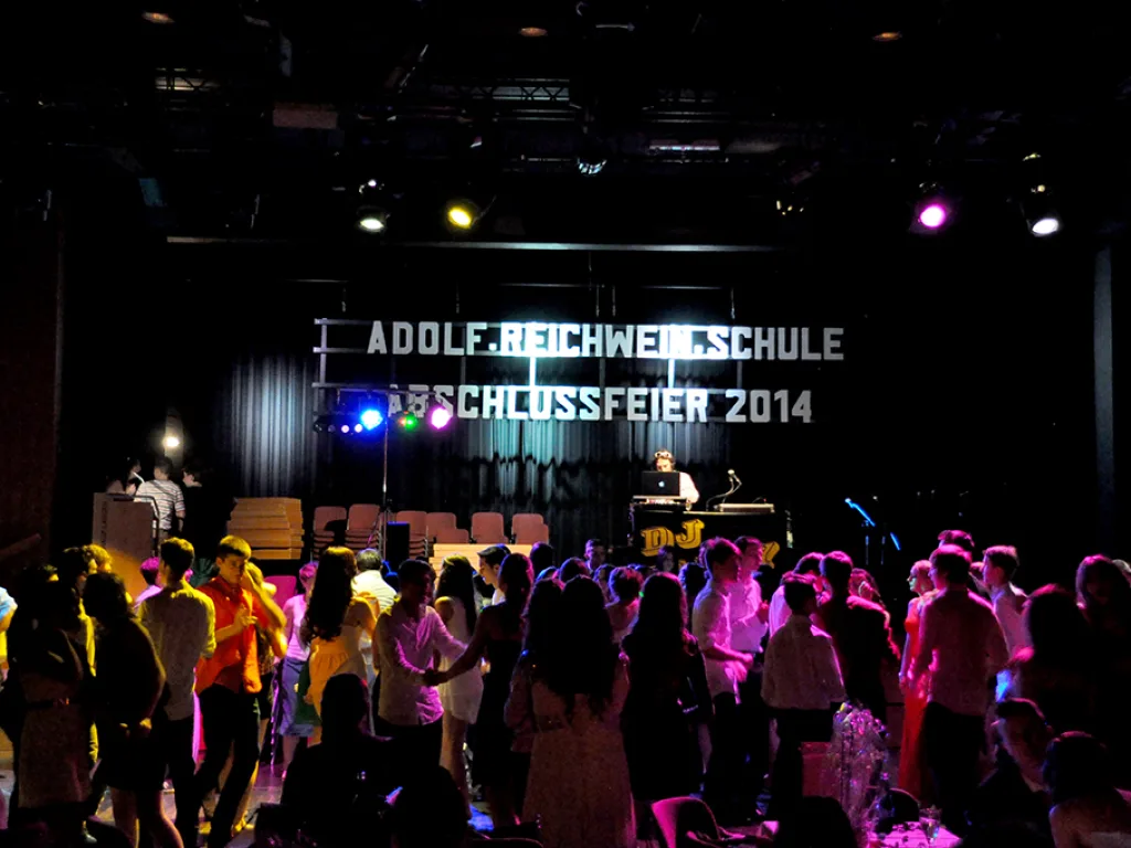 Volle Tanzfläche vor der beleuchteten Schriftwand.